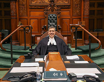 Clerk of the Assembly sitting at the table in the legislative Chamber