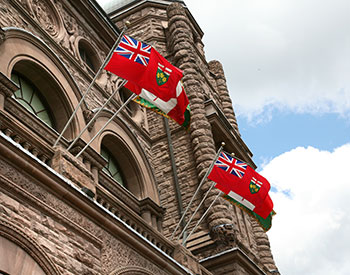 two Ontario flags flying in front of the Legislative Building