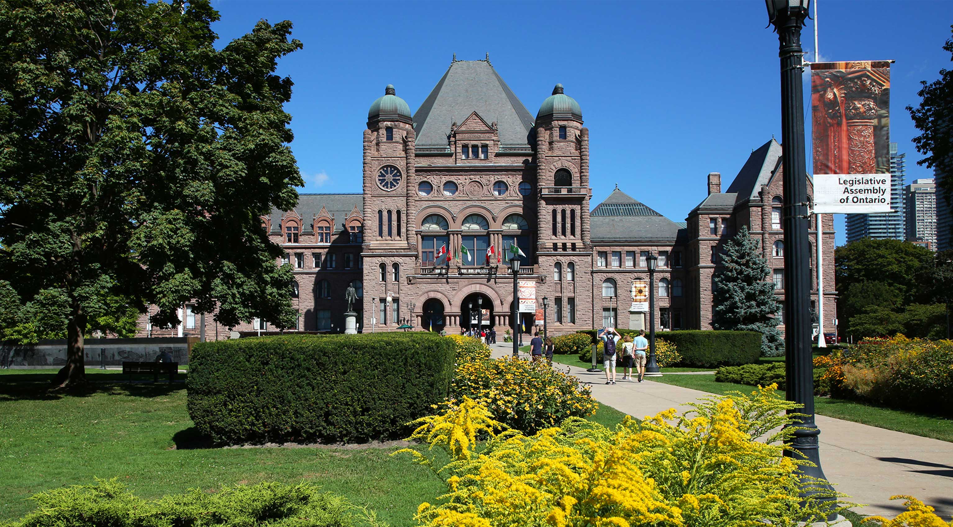 front lawn of Legislative Assembly with trees and buildings in background