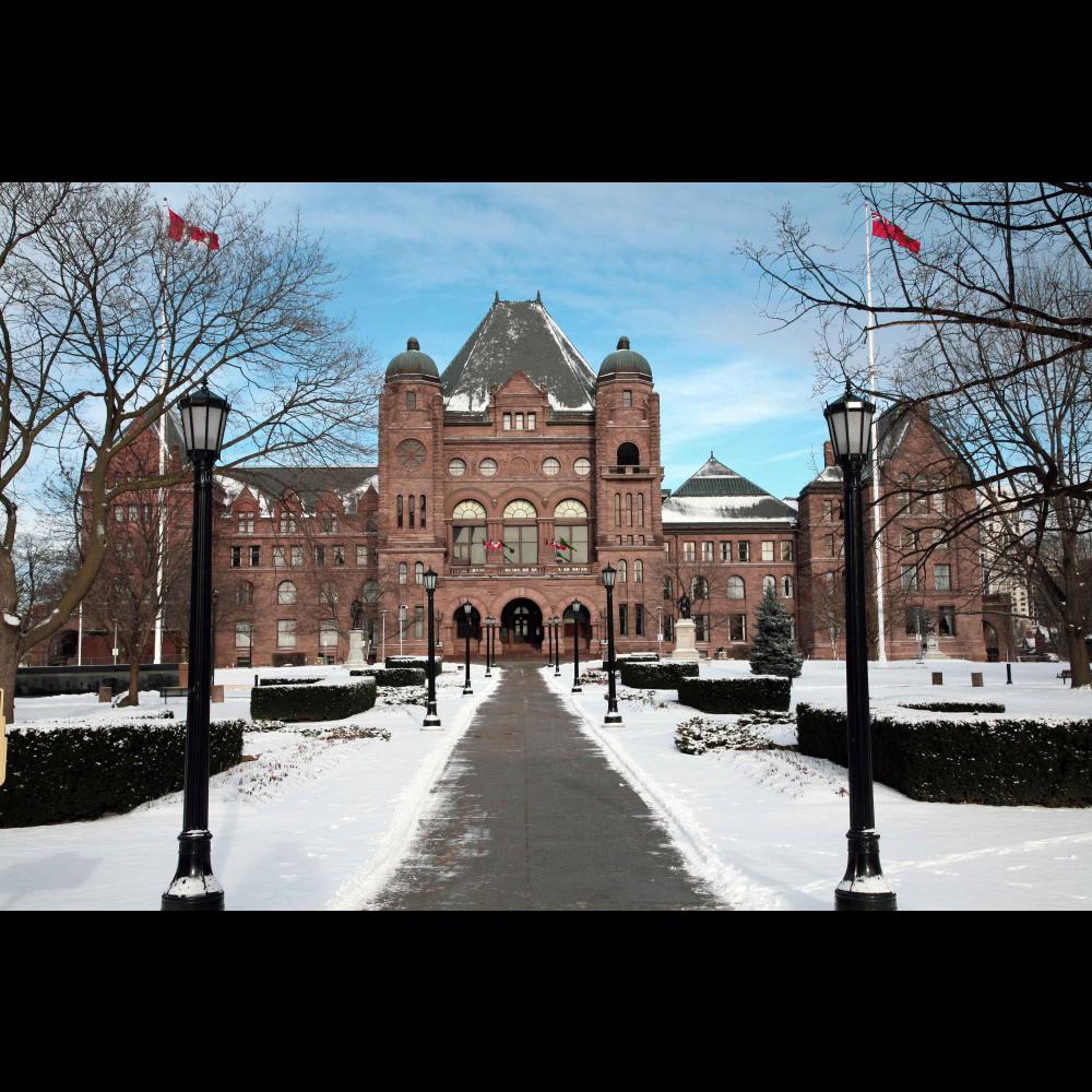 A front view of the Legislative building in winter surrounded by snow.